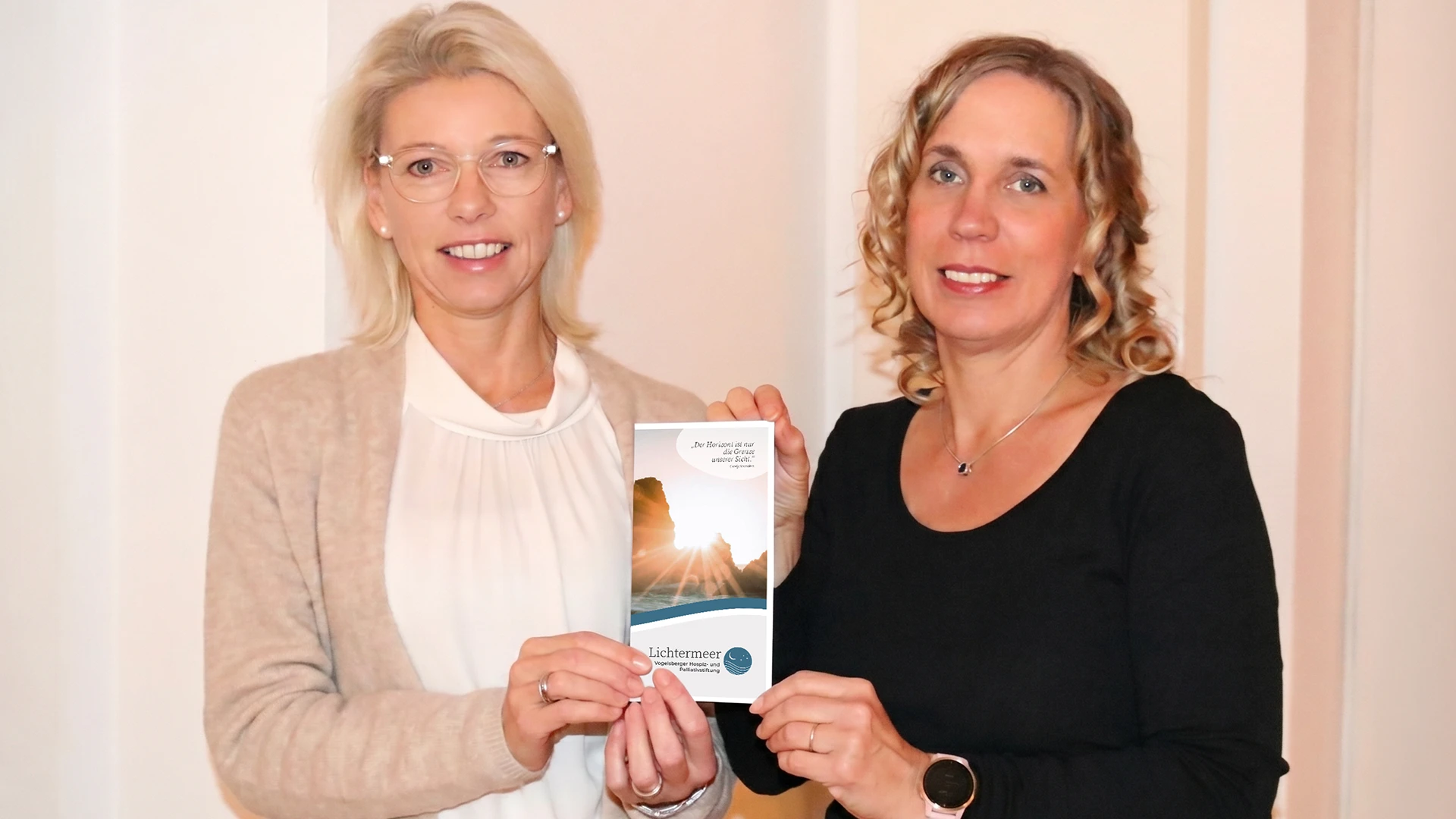 Tanja Bohn und Barbara Becker präsentieren lächelnd den neuen Informationsflyer der Lichtermeer Stiftung.